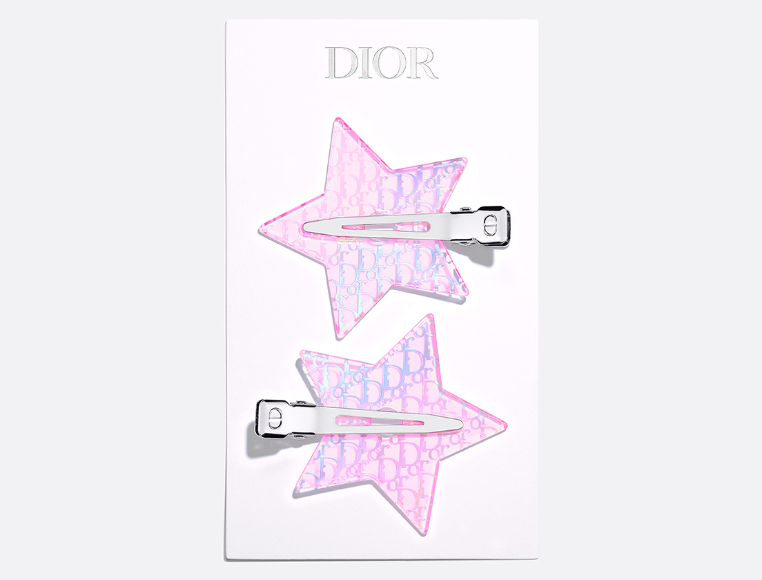 Een paar roze haarclips in de vorm van een ster, versierd met een holografisch Dior-motief.