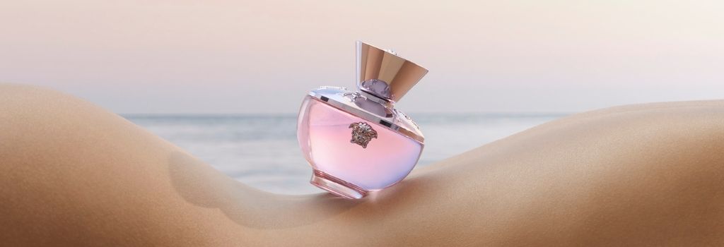 Versace Dylan Blush Pink perfume bottle displayed tilted on dunes with the sea in the background,