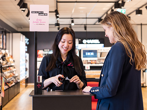 Conseiller d'ICI PARIS XL remettant un échantillon de produit à un client lors d'un service d'échantillonnage en magasin.
