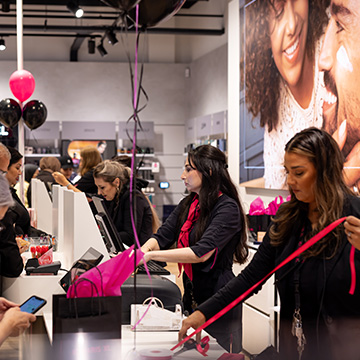 Des clients sont servis aux caisses d'un magasin ICI PARIS XL, tandis que des collaborateurs emballent des achats lors d'un moment d'affluence.