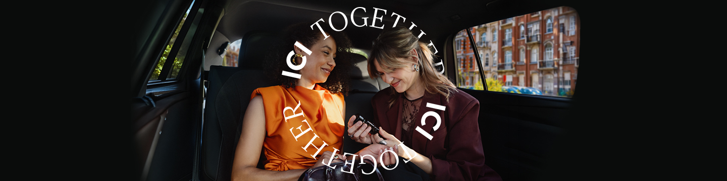 Deux jeunes femmes souriantes, amies, dans un taxi, avec un parfum ICI PARIS XL. Le texte « ICI Together » est visible