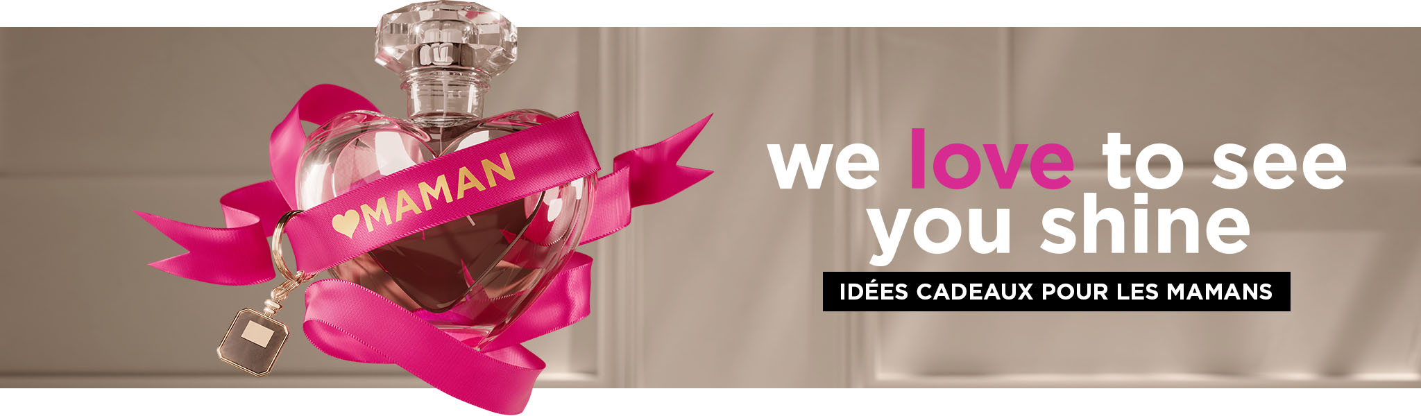 Un flacon de parfum en forme de cœur entouré d'un ruban portant l'inscription « MOM »