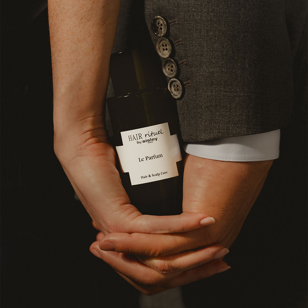 Mains tenant le flacon Le Parfum Hair Rituel by Sisley