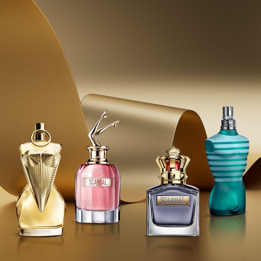 Jean Paul Gaultier Gaultier Divine, Scandal, Scandal Pour Homme and Le Male perfumes displayed against a gold background.