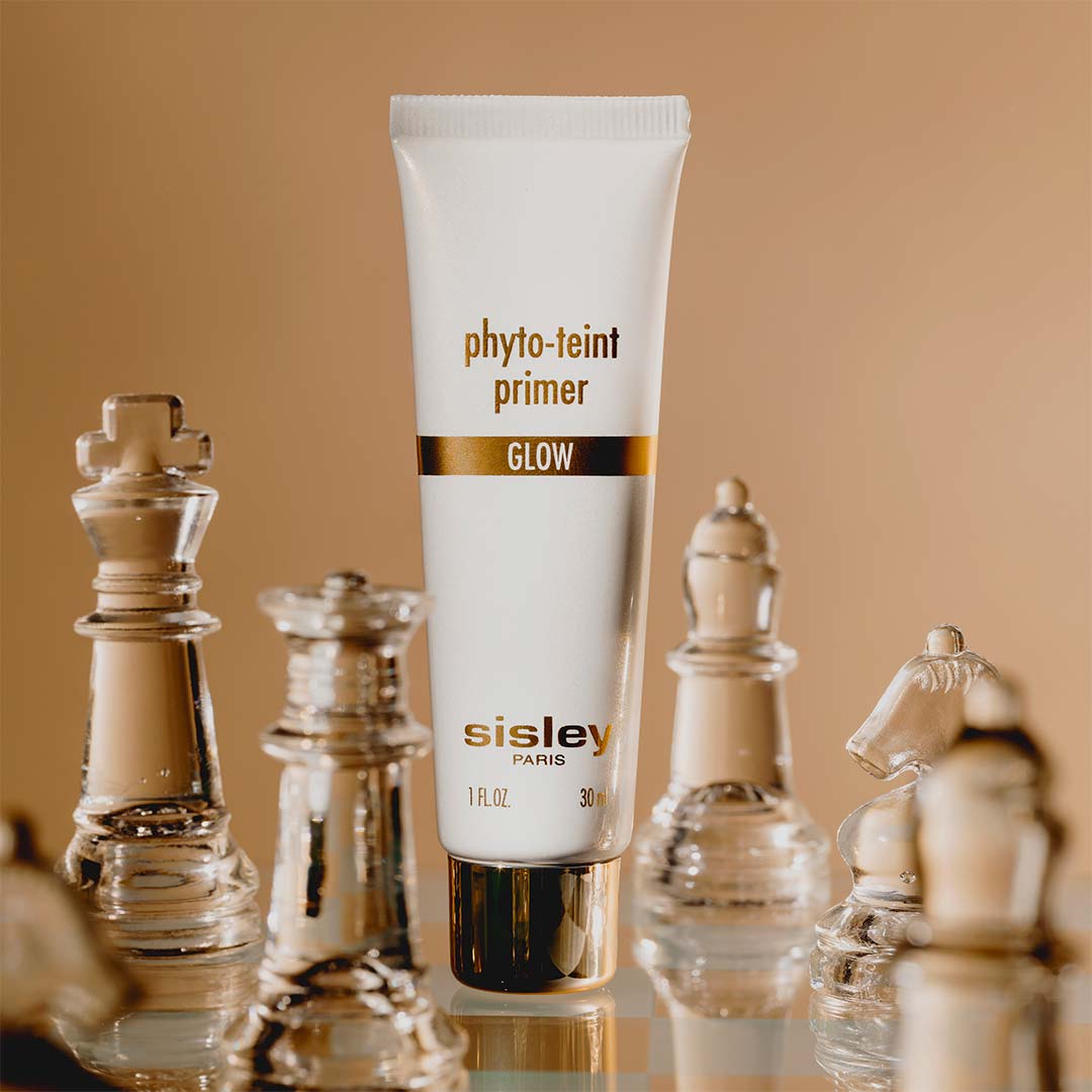 Phyto-Teint Primer Glow de Sisley entouré de pièces d’échecs en verre