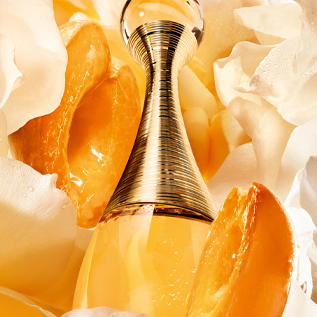 Le flacon de l’Eau de Parfum J’adore, entourée d’abricots et de jasmin.