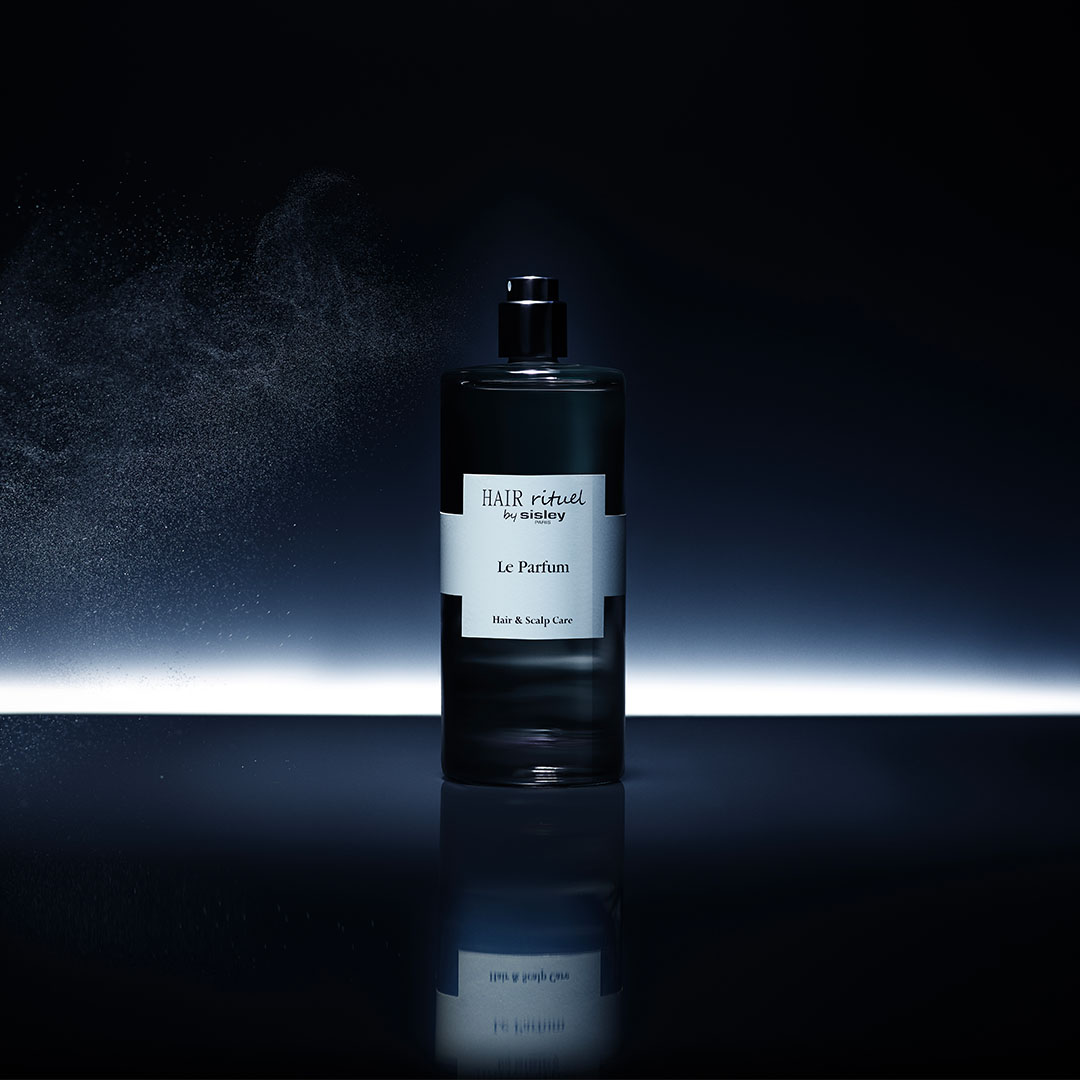 Flacon Le Parfum Hair Rituel by Sisley avec brume sur fond sombre