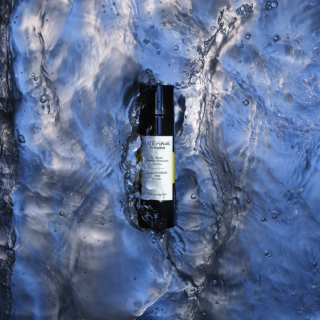Hair Rituel by Sisley Protective Shield Mist bottle lying in flowing blue water