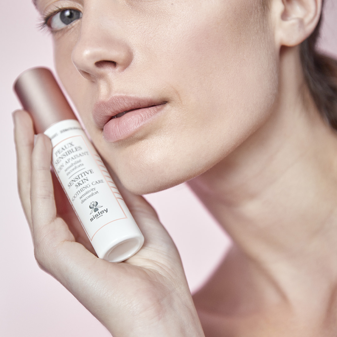 Woman applying Sisley Sensitive Skin Soothing Care to cheek