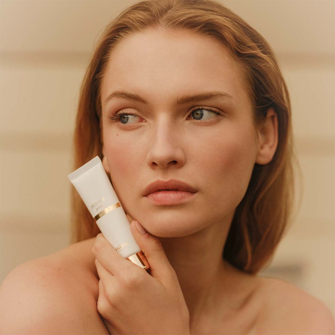 Femme tenant le Phyto-Teint Primer Glow de Sisley contre son visage
