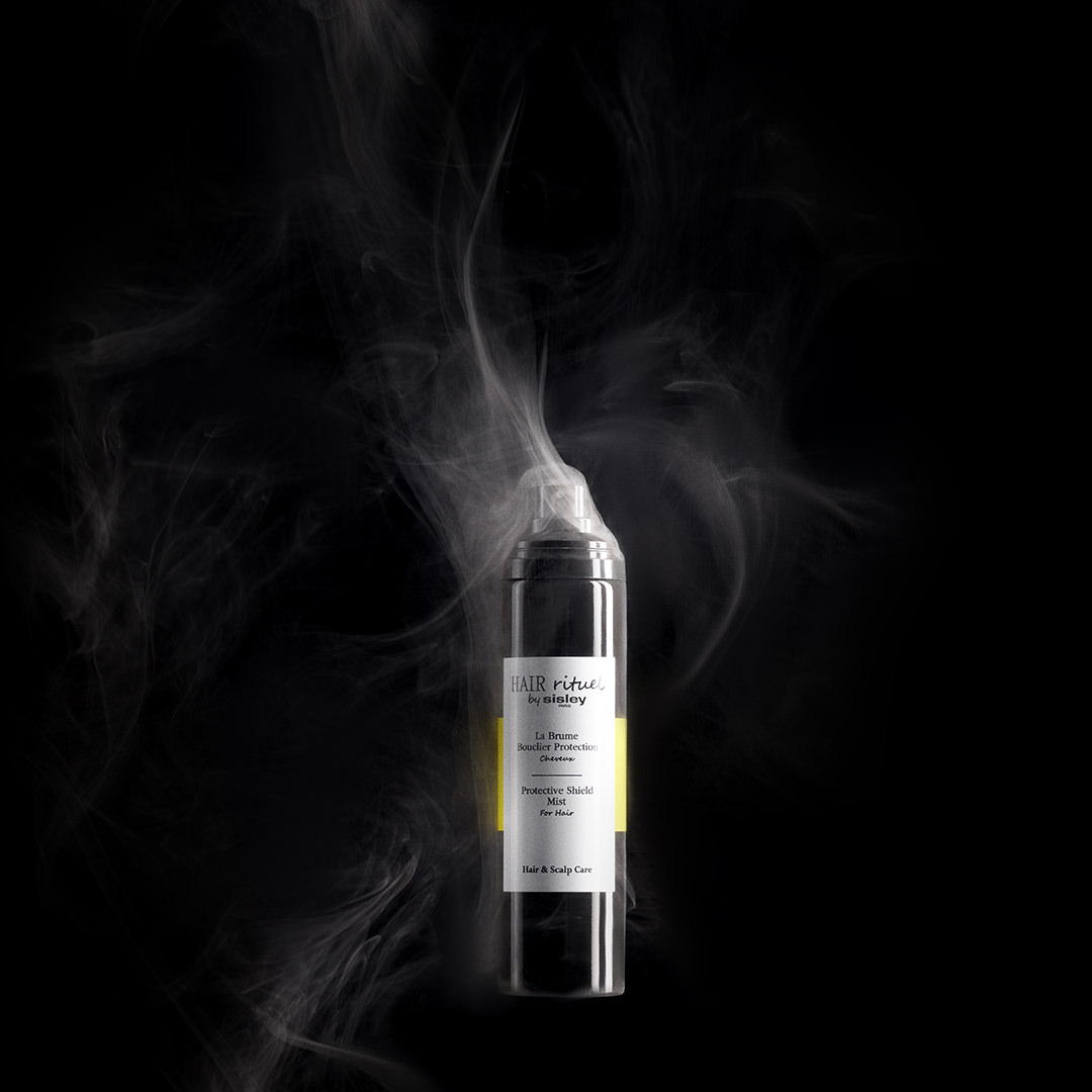 Hair Rituel by Sisley Protective Shield Mist emitting mist against a black background