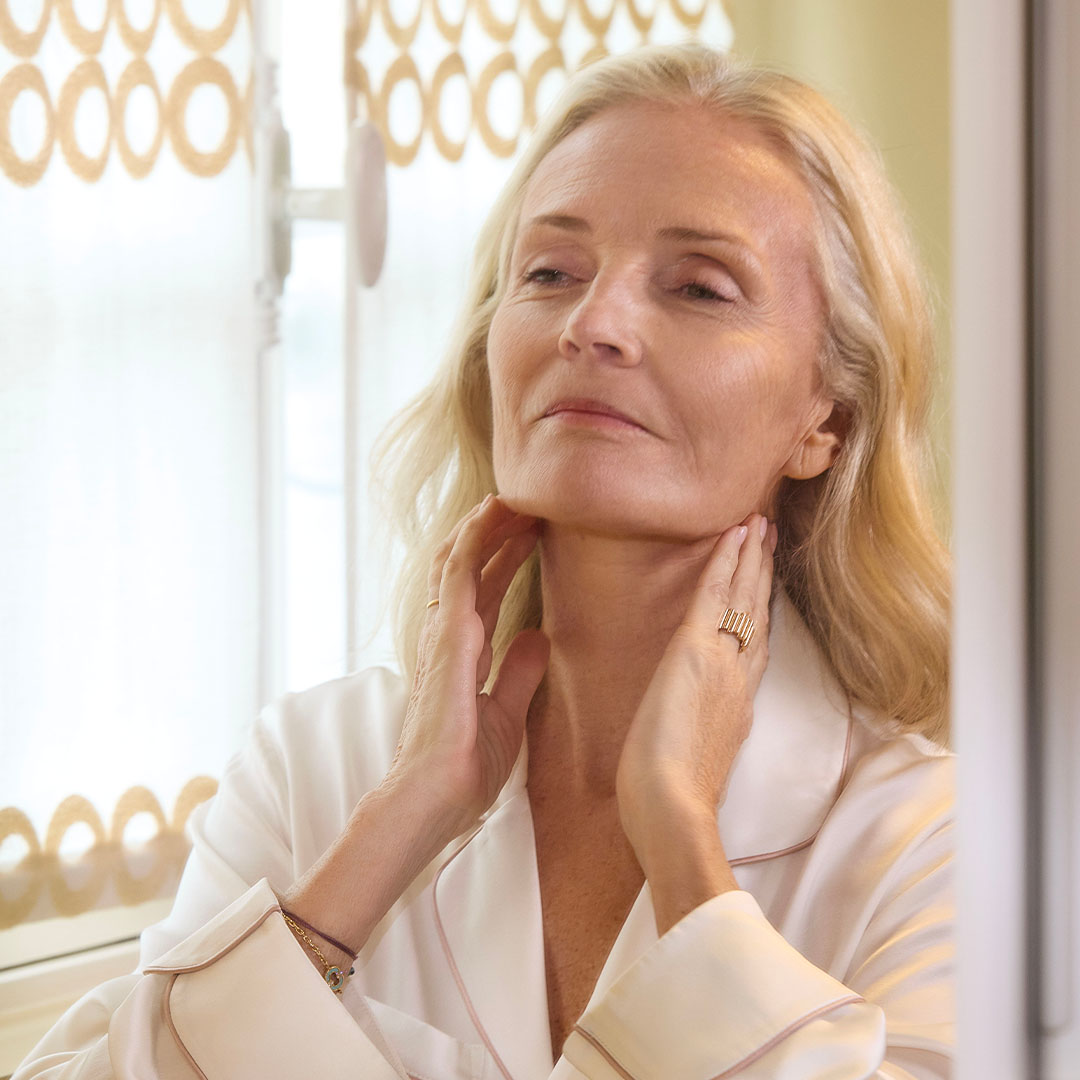 Femme appliquant un soin sur son cou devant un miroir