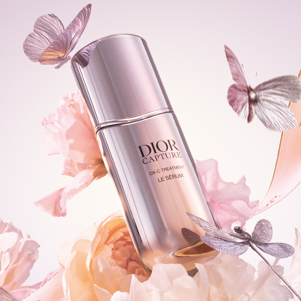 Dior Capture Le Sérum flacon op een achtergrond van bloemen en vlinders