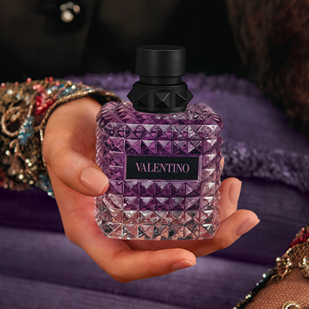 Close up shot of hand holding Born in Roma Purple Melancholia perfume.